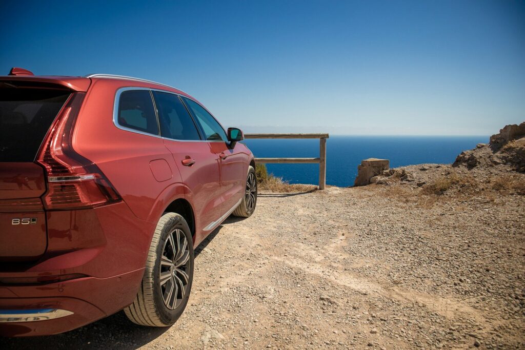 a red car parked on a rocky beach